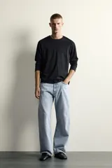Jeans de denim de algodón en color azul con efecto desgastado, tiro medio y corte recto de ajuste holgado (loose fit). Cuenta con diseño clásico de cinco bolsillos y cierre frontal con cremallera y botón.