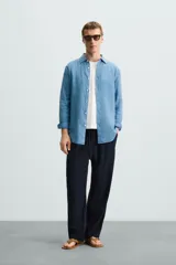 Camisa de corte regular fit confeccionada en tejido de lino, con cuello solapa, manga larga con puños abotonados y cierre frontal de botones.