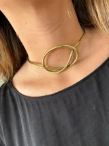 Gargantilla rígida dorada con forma de nudo. Hecha artesanalmente en bronce.