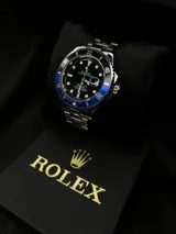 Reloj Rolex Submariner "Batman" con bisel giratorio unidireccional negro y azul, esfera negra con índices luminiscentes, lupa sobre la ventana de fecha y malla de acero inoxidable.