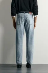 Pantalón jeans de corte recto, color celeste claro con efecto lavado, de cinco bolsillos y tiro medio.
