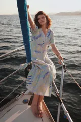 Vestido midi celeste con estampado de hojas en tonos lila y verde, corte evasé, cuello camisero, manga corta y falda escalonada.