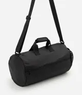 Bolso deportivo cilíndrico de poliéster color negro, con amplio espacio interior, cierre superior con cremallera, asas de mano reforzadas, asa transversal regulable y desmontable, bolsillo frontal con cremallera y bolsillo lateral de malla.