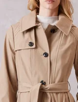 Gabardina trench de tejido repelente al agua en color beige. Presenta cuello con solapa ancha, cierre frontal con botones en tono carey, capucha desmontable y lazo de ajuste en la cintura. Incluye bolsillos laterales tipo ojal y forro interno a tono.