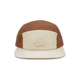 Gorra de cinco paneles con diseño bicolor que combina paneles laterales de poliéster marrón con panel frontal y visera plana de corderoy color crema. Incluye un parche hexagonal con relieve en el frente.