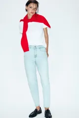 Jeans tipo mom fit de tiro alto color blanco, con diseño de cinco bolsillos, cierre frontal con cremallera y botón, y corte tobillero.
