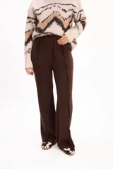 Pantalón de tejido de punto color marrón, de corte recto y holgado. Presenta costuras verticales decorativas con efecto desflecado a lo largo de las piernas y cintura elástica con cordón de ajuste.