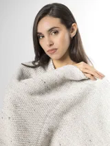 Ruana de punto color beige con sutiles motas multicolores, con bordes terminados en flecos largos.