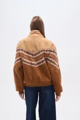 Chaqueta holgada de poliéster en color tostado con forro de corderito, cuello de solapa y cierre frontal con botones. Presenta mangas con apliques de diseño geométrico en tonos marrones y azules.
