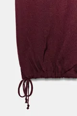 Pantalón de punto color bordó, tiro medio, con cintura elástica y puños ajustables con lazada en los tobillos.