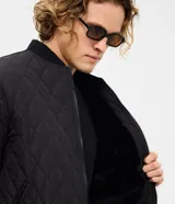Campera masculina de corte regular, confeccionada en poliéster con acabado capitoneado texturizado en rombos. Presenta cierre frontal con cremallera, cuello redondo y puños con terminación en rib.