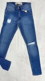 Pantalón de jean chupín color azul claro con roturas en ambas rodillas y en el muslo.