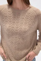 Sweater de algodón color beige con diseño de punto en relieve en forma de zigzag y pequeños puntos. Tiene cuello redondo y mangas largas tipo ranglán.