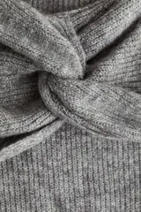 Buzo de punto acanalado con escote off-the-shoulder y detalle de nudo frontal. Presenta mangas largas y diseño ajustado.