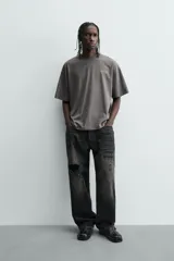 Camiseta de manga corta y cuello redondo, color gris oscuro con efecto lavado. Presenta un pequeño estampado en el pecho con texto en color verde lima.