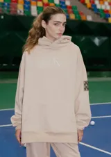 Buzo oversize color nude confeccionado en frisa, con capucha amplia, bolsillo canguro, terminaciones de puño y ruedo con rib, y logo de la marca bordado en el centro delantero.