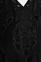 Top de escote en pico con tirantes finos, confeccionado en tejido satinado negro. Presenta bordados decorativos en el frente y un bajo asimétrico con detalle de puntilla de encaje.
