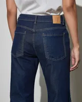 Jean de denim azul oscuro con diseño acampanado y costuras decorativas a contratono en las piernas.