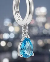 Caravanas colgantes de plata 925 con diseño de doble gota, una superior con pavé de circonias blancas y una inferior con una circonia central color celeste.