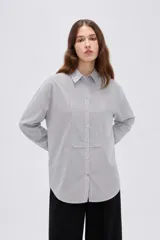 Camisa de algodón a rayas grises y blancas, de corte holgado, con cuello camisero, manga larga y cierre frontal de botones.