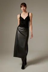 Falda midi de eco-cuero negro con corte recto y tajo lateral, incluye cinturón con hebilla metálica.