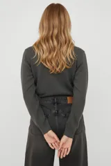 Cardigan de punto color natural con cuello redondo y cierre frontal de botones. Presenta un delicado bordado de lazos en la parte superior del pecho y puños acanalados.