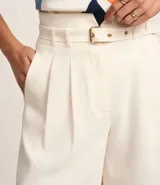 Bermuda de sastrería color crudo, de corte recto y cintura alta, con trabillas, cinturón y cierre por cremallera.