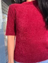 Buzo de punto texturizado con efecto peluche, color bordó, de cuello redondo y manga corta.