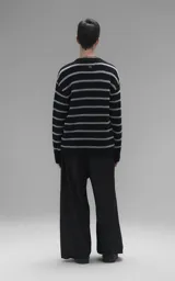 Sweater de cuello redondo con diseño de rayas horizontales en negro y gris. Presenta una textura suave y peluda, con terminaciones en punto rib en el cuello.