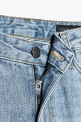 Jeans de tiro alto con corte recto y efecto lavado. Cuenta con cinco bolsillos, trabillas en la cintura y cierre frontal con cremallera y botón.