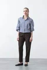 Camisa a rayas azules y blancas de manga larga, con cuello clásico y puños abotonados. Presenta un diseño entallado en la cintura.