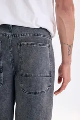 Pantalón de jean estilo skater color gris claro, de corte amplio y relajado, con bolsillos laterales grandes.