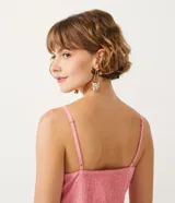 Blusa musculosa de color rosado confeccionada en tejido laise de algodón. Presenta un escote en V con un lazo decorativo en el frente, tirantes finos y detalle de lastex en la espalda para un mejor ajuste.