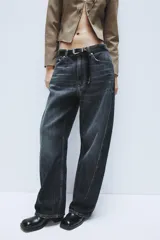 Jeans de tiro medio con diseño baggy barrel, confeccionados en denim color beige con efecto lavado. Presentan cinco bolsillos, costuras laterales torcidas y cierre frontal con cremallera y botón metálico.
