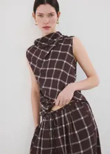 Pantalón balloon de tiro medio en color marrón oscuro con estampa de cuadros. Cuenta con cintura ajustable con goma y cierre de lazo, además de dos bolsillos laterales y diseño abuchonado en los tobillos.