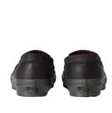 Championes Vans tipo mocasín de cuero negro, con diseño inspirado en el skate y estética clásica. Presenta detalles de tachuelas metálicas en la lengüeta, construcción vulcanizada y suela waffle de goma gris oscuro.
