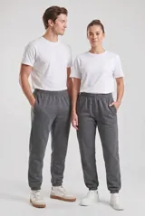 Pantalón de jogging unisex de corte recto y ajuste holgado, confeccionado en tejido de algodón y poliéster. Presenta cintura elástica con cordón interno, bolsillos laterales y puños elásticos en los tobillos.