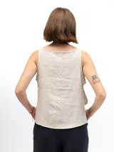 Musculosa beige de lino con cuello redondo y laterales abiertos unidos por tres lazos cosidos.