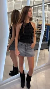 Top negro con escote halter y múltiples volados horizontales en cascada.