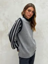 Sweater de lana color crudo con mangas largas abullonadas en gris y blanco, con diseño de rayas y perforaciones. Cuello redondo y puños acanalados.