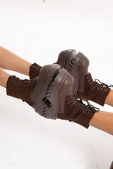 Borcego acordonado de caña media con plataforma alta de goma dentada. Presenta una combinación de texturas en cuero y gamuza en tono marrón oscuro, con cierre de cordones al frente y ojales metálicos.