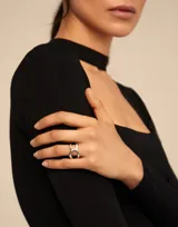 Anillo de metal bañado en plata con diseño curvilíneo de estilo oriental y logo de la marca grabado.