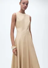 Vestido midi de corte evasé en color beige, confeccionado en una mezcla de algodón y lyocell. Presenta cuello redondo, diseño sin mangas con tirantes anchos, costuras estructuradas y bajo asimétrico con acabado deshilachado. Incluye cierre de cremallera en la parte posterior y forro interior de algodón.