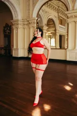 Conjunto de lencería rojo vibrante, compuesto por un corpiño sin aro, una falda de tul con ligas incorporadas y una gargantilla a juego con detalle de fleco colgante.