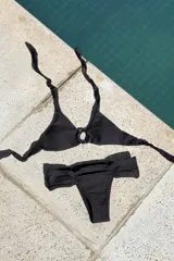 Conjunto de bikini con estampado a cuadros, compuesto por un corpiño triangular con argolla y tiras para atar al cuello y espalda, y una bombacha vedetina ancha con frunces delanteros y traseros.