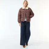 Campera acolchada corta color marrón con cuello de borreguito color crema. Presenta cierre frontal con botones a presión y bolsillos con solapa en el pecho.