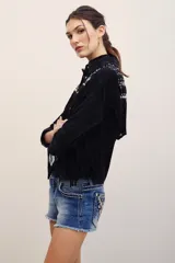 Short de denim azul de tiro bajo, con lavado desgastado, dobladillo desmechado y bolsillos traseros con bordados ornamentales y tachas metálicas.