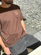 Remera marrón de corte oversize con estampado pequeño en el pecho.