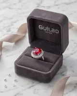 Anillo de plata 925 con piedra central ovalada de raíz de rubí en color rojo intenso, rodeada por un engaste de circonias brillantes.