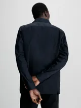 Camisa negra de popelina con corte relaxed, cierre frontal con botones, mangas largas y dos bolsillos con solapa en el pecho.